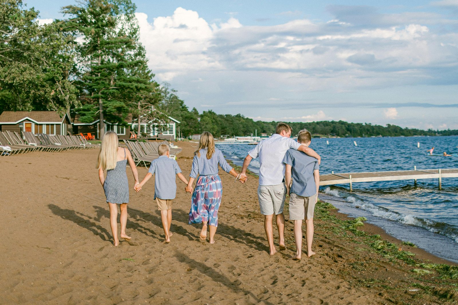 A family walking arm in arm along the beach at a lakeside resort